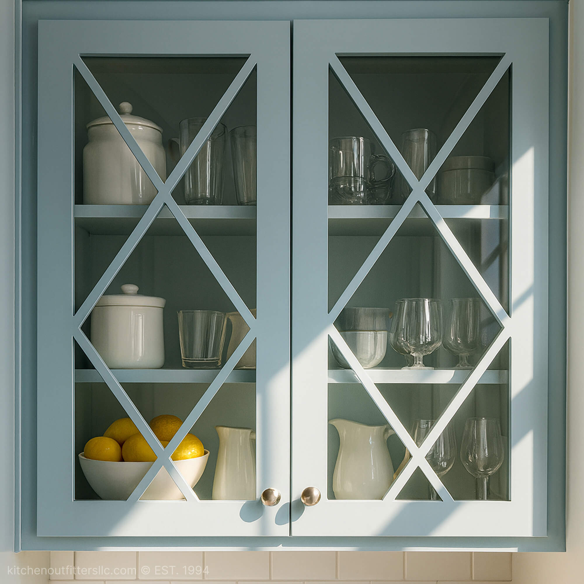 Double X mullion glass cabinet doors in soft blue kitchen cabinet with decorative grid pattern and glass panels